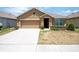 Tan one-story house with two-car garage and landscaping at 1843 Brockridge Rd, Kissimmee, FL 34744