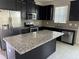 Modern kitchen with dark cabinets, granite island, and stainless steel appliances at 2757 Creekmore Ct, Kissimmee, FL 34746