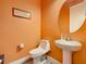 Small powder room with pedestal sink and orange walls at 2516 Pickett Ave, Saint Cloud, FL 34772