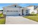 Front view of a one-story house with gray siding, stone accents, and a two-car garage at 4043 Bannock Ave, Tavares, FL 32778