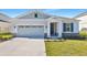 Curb appeal of a one-story house featuring gray siding, stone accents, and a two-car garage at 4043 Bannock Ave, Tavares, FL 32778