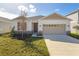 Newly built house with beige exterior, two-car garage, and red shutters at 171 Bull Frog Ln, Umatilla, FL 32784