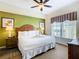 King-size bed in a well-lit bedroom with a green accent wall and a ceiling fan at 8125 Resort Village Dr # 51104, Orlando, FL 32821