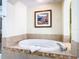 Oval soaking tub with tile surround and framed coastal artwork above at 8125 Resort Village Dr # 51104, Orlando, FL 32821