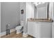 Modern powder room with granite countertop and white cabinetry at 494 Muirfield Loop, Reunion, FL 34747
