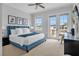 Main bedroom with a blue upholstered bed, access to a private balcony and sitting area at 494 Muirfield Loop, Reunion, FL 34747