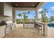 Outdoor kitchen with grill, refrigerator, and bar seating overlooking pool at 1125 Grand Traverse Pkwy, Reunion, FL 34747