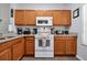 Updated kitchen with wood cabinets, granite counters, and white appliances at 2758 Sun Key Pl, Kissimmee, FL 34747
