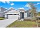 One-story home with gray siding, stone accents, and a two-car garage at 4063 Bannock Ave, Tavares, FL 32778