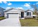 One-story home with gray siding, stone accents, and a two-car garage at 4063 Bannock Ave, Tavares, FL 32778