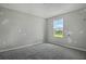 Simple bedroom with grey walls and carpet, featuring one window at 180 Flag Lilly Ln, Umatilla, FL 32784