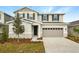 Two-story home with neutral siding, stone accents, and a two-car garage at 180 Flag Lilly Ln, Umatilla, FL 32784