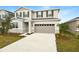 Two-story home with neutral siding, a stone facade, and a two car garage at 180 Flag Lilly Ln, Umatilla, FL 32784