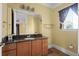 Guest bathroom with granite countertop, wood cabinets, and a window at 7459 Gathering Dr, Reunion, FL 34747