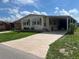 Single-wide manufactured home with carport and mature landscaping at 5013 Foxwood Blvd, Lakeland, FL 33810