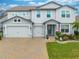 Two-story house with gray siding, three-car garage, and landscaped yard at 2867 Matera Dr, St Cloud, FL 34771