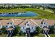 Aerial view showing townhouses near a pond and lush green space at 8971 Stinger Dr, Davenport, FL 33896