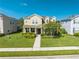 Two-story house with light beige siding, landscaping, and a walkway at 2662 Trafalgar Blvd, Kissimmee, FL 34758