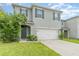 Two-story house with gray siding, white garage door, and landscaping at 6728 Huntleigh Hammock Rd, Harmony, FL 34773