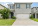 Two-story house with gray siding, white garage door, and landscaping at 6728 Huntleigh Hammock Rd, Harmony, FL 34773