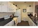 Modern kitchen with white cabinets, black countertops, and stainless steel appliances at 7671 Comrow St # 302, Kissimmee, FL 34747