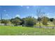 Open grass area with a wooden fence and trees under a bright sky at 108 Country Walk Cir, Davenport, FL 33837