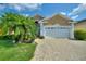 Tan house with white garage door, landscaping, and paved driveway at 220 Lewis Dr, Davenport, FL 33837