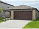 A brown garage door, concrete driveway, and well-manicured lawn at 1629 Yellow Trl, Lakeland, FL 33801