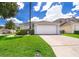 Single story home with attached garage and well-manicured lawn at 104 Langham Dr, Davenport, FL 33897