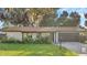 Updated ranch home exterior boasts a newly painted stone facade, dark brown garage door, and lush green lawn at 3722 Paige St, Port Orange, FL 32129