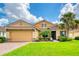 Tan two-story house with a large garage and lush landscaping at 316 Treviso Dr, Poinciana, FL 34759