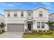 Two-story house with a gray garage door and landscaping at 3209 Lilac Way, Davenport, FL 33897
