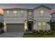 Two-story house with a gray garage door and landscaping at dusk at 3209 Lilac Way, Davenport, FL 33897
