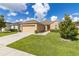 Tan house with a red door, two-car garage, and green lawn at 3663 Julius Estates Blvd, Winter Haven, FL 33881