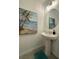Small powder room with pedestal sink, framed mirror, and beach-themed artwork at 718 Longboat Dr, Davenport, FL 33896