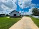 Large grassy backyard with a long driveway and partial home view at 1980 Poblado Ct, Kissimmee, FL 34744