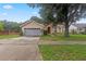 Tan two-car garage home with mature tree in the front yard at 2771 Cedaridge Cir, Clermont, FL 34711