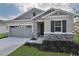 One-story home with gray siding, stone accents, and a two-car garage at 4216 Sawtooth Ct, Tavares, FL 32778