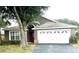 One-story house with a gray exterior, lush landscaping and a white garage door at 2556 Bear Creek Ct, Kissimmee, FL 34747