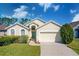 Tan house with two-car garage and landscaping at 443 Corvina Dr, Davenport, FL 33897