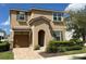 Two-story tan house with a brown door, two-car garage, and manicured landscaping at 1612 Herrons Green Path, Kissimmee, FL 34747