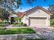 Single-story home with red tile roof, beige exterior, and two-car garage at 722 Coronado Dr, Kissimmee, FL 34759