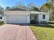 White house with gray roof, a two-car garage, and a brick paver driveway at 1620 9Th Ave, Deland, FL 32724