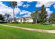 Single-story home with a red door, lush lawn, and palm trees at 2918 Sunset Retreat Ct, Kissimmee, FL 34747