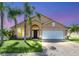 Tan two-story house with a dark brown door and lush landscaping at 621 Knightsbridge Cir, Davenport, FL 33896