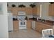 Kitchen with light wood cabinets, white appliances, and tile floor at 608 Copeland Dr, Haines City, FL 33844