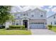Two-story house with gray siding, stone accents, and a three-car garage at 1676 Moon Valley Dr, Davenport, FL 33896