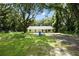 Newly built home nestled amongst mature trees with a gravel driveway at 424 Wilder Rd, Lakeland, FL 33809