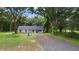 Newly built home nestled amongst mature trees with a gravel driveway at 424 Wilder Rd, Lakeland, FL 33809