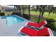 Screened pool and patio with red lounge chairs at 1652 Dunes Ct, Haines City, FL 33844